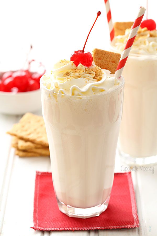 two glasses filled with milkshakes and topped with whipped cream, cherries and graham crackers