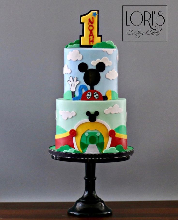 a mickey mouse birthday cake on top of a wooden table with the number one on it