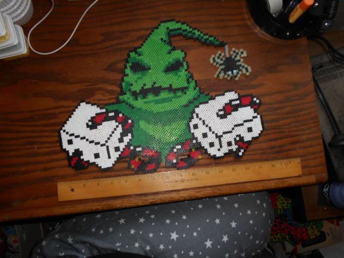 a wooden table topped with a cross stitched image of an angry green creature on it