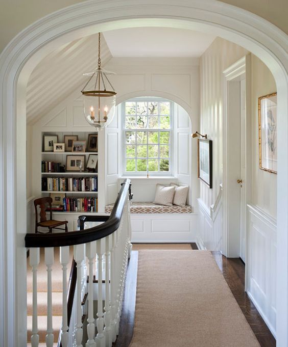 an archway leading to a living room with a window seat and bookshelf in the corner