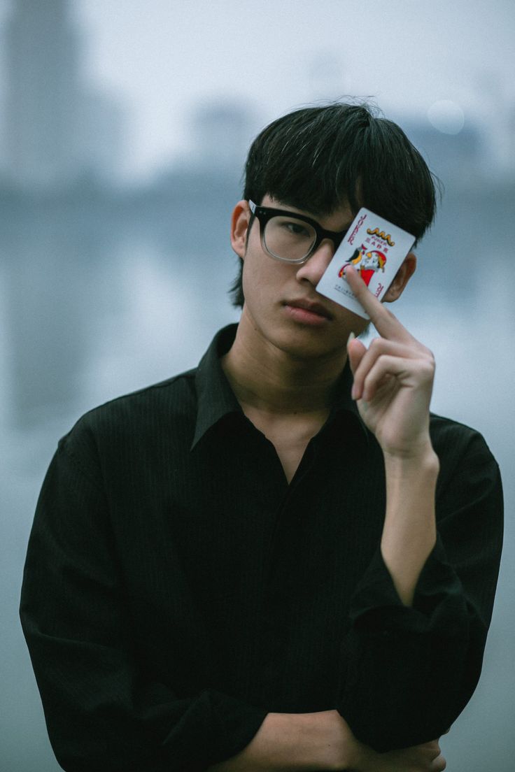 a man with glasses holding up a card in front of his face