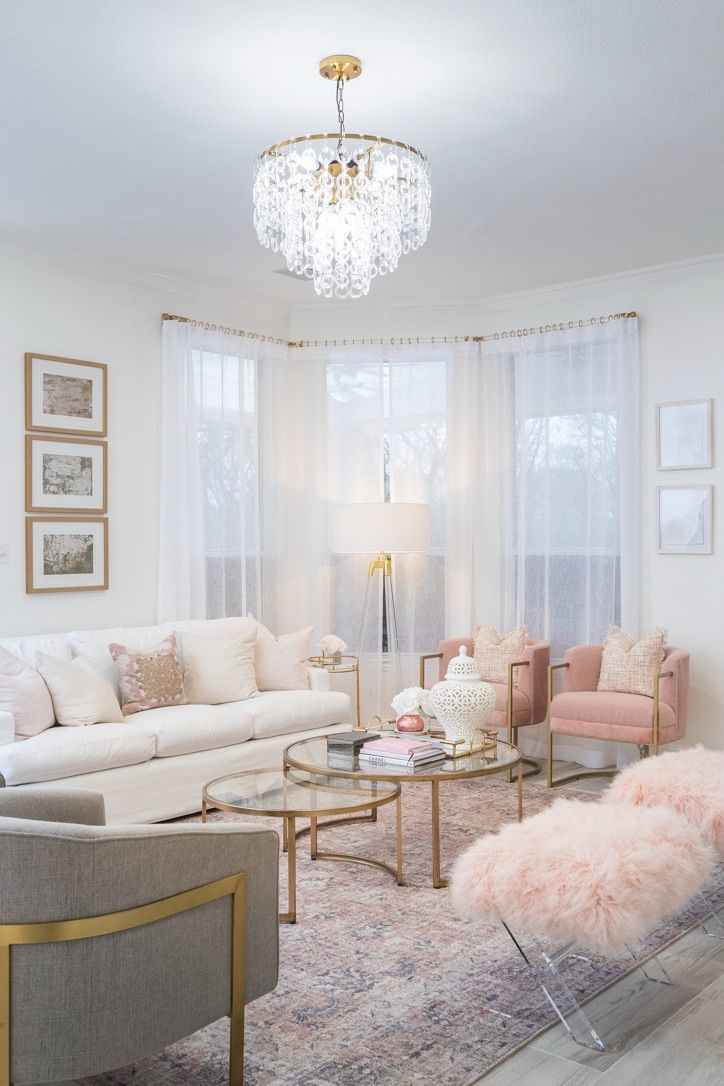 a living room filled with furniture and a chandelier hanging from the ceiling over a window