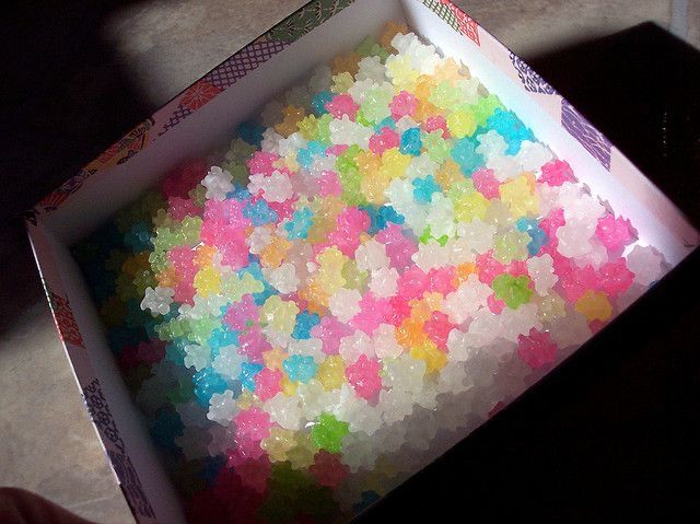 a box filled with lots of colorful confetti on top of a table next to a persons hand