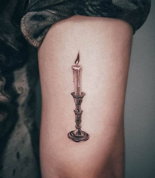 a small candle tattoo on the arm