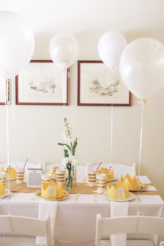 the table is set with white and yellow balloons