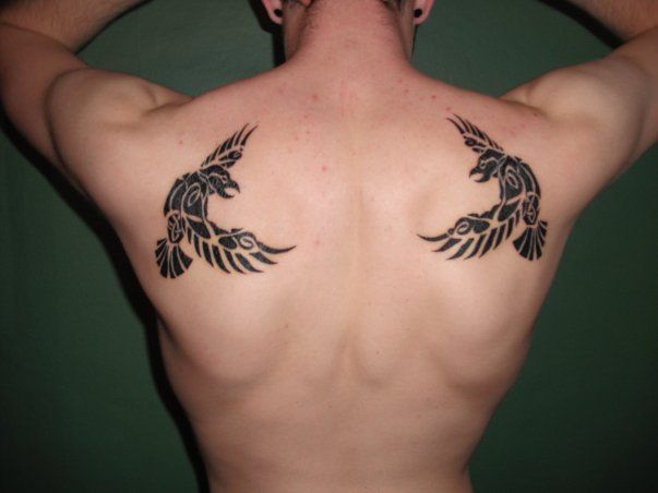 the back of a man with tattoos on his upper and lower part of his body