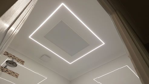 an empty bathroom with white walls and lights on the ceiling