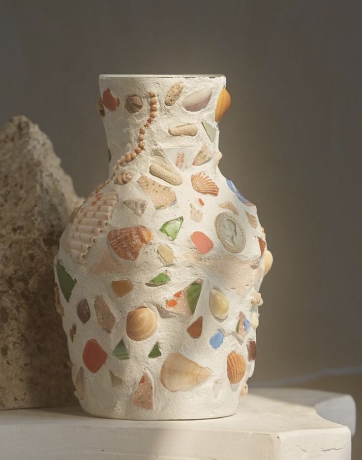 a white vase with shells and seashells on it