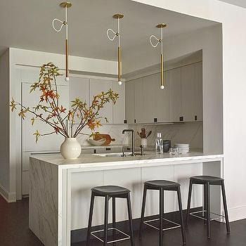 a kitchen with three stools next to an island