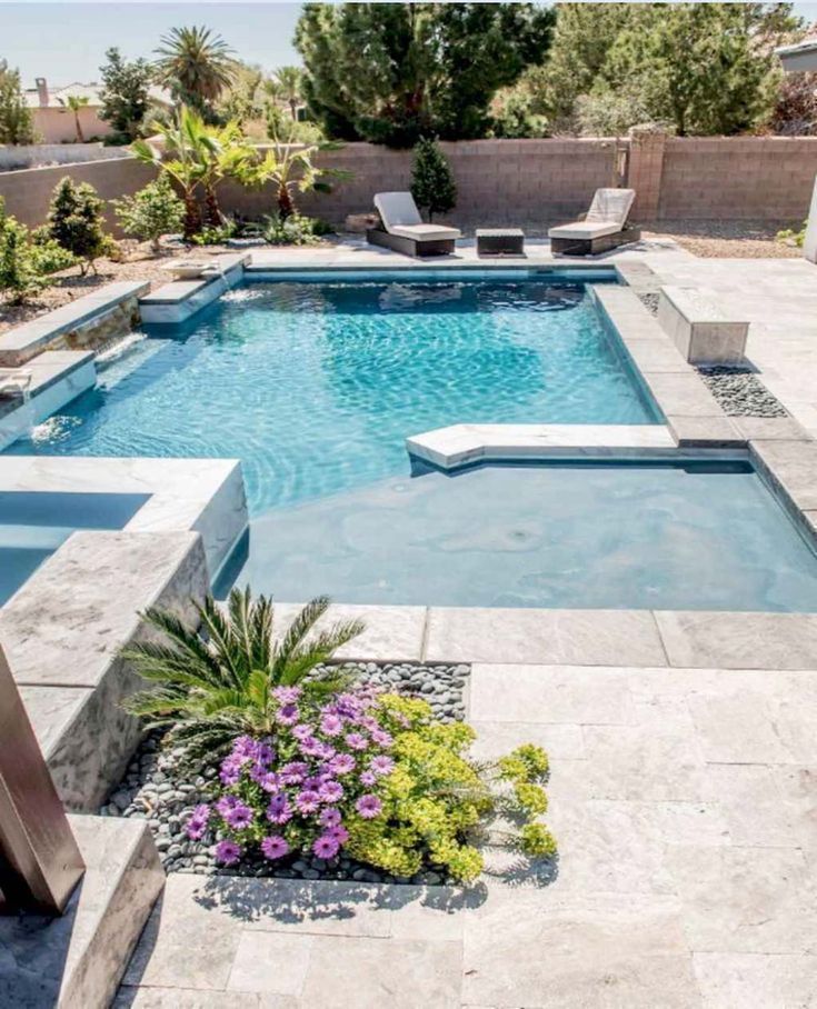 a small pool surrounded by plants and flowers in the middle of a backyard with seating area