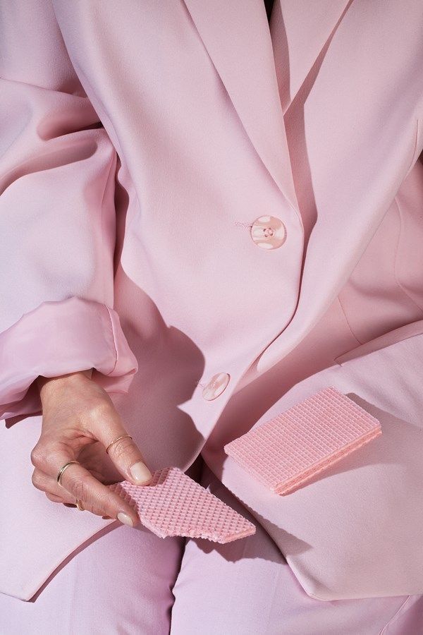 a person in a pink suit and tie holding a pink piece of cloth on their lapel