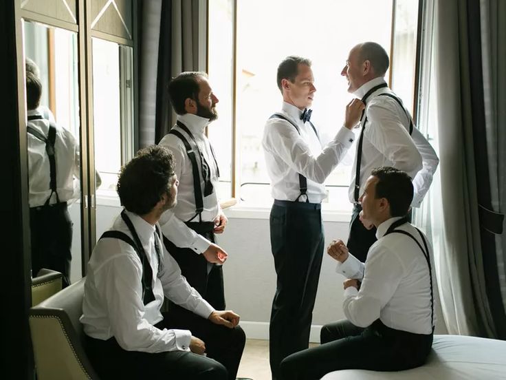 a group of men standing next to each other in front of a window with ties on