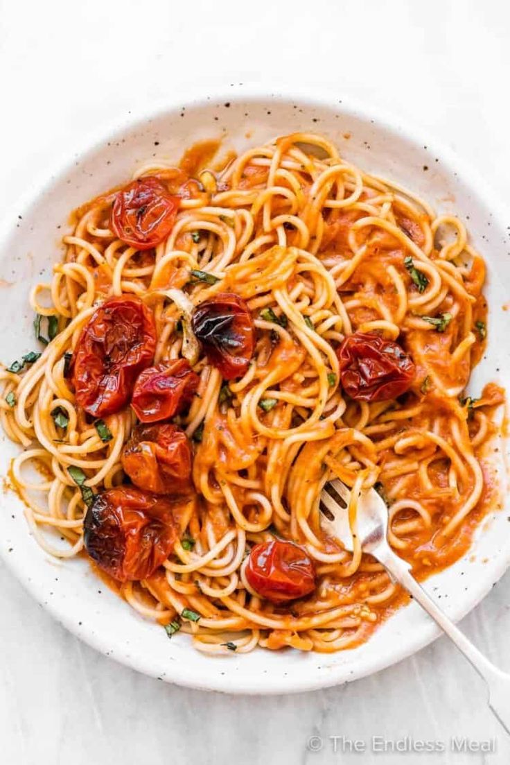 a white bowl filled with pasta and tomato sauce