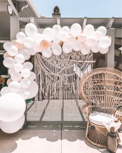 white balloons are hanging from the ceiling in front of an outdoor area with wicker furniture