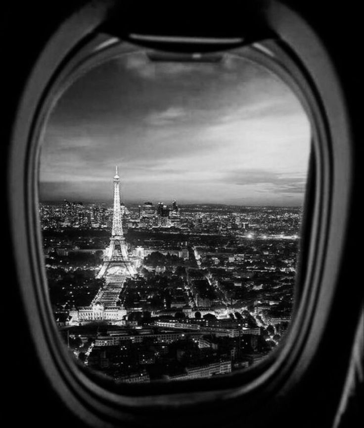 an airplane window looking out at the eiffel tower and paris, france in black and white