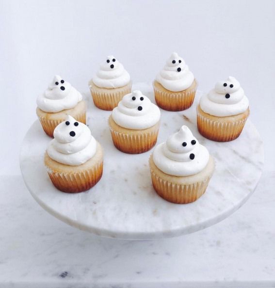 cupcakes with white frosting and black sprinkles on a marble platter