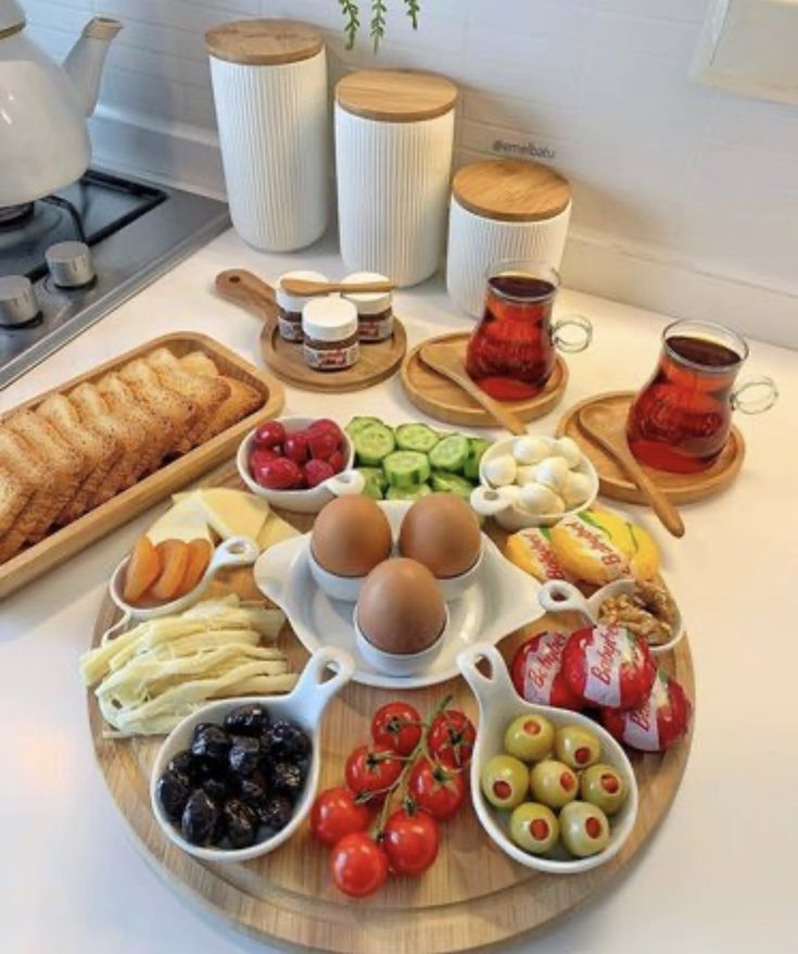 an assortment of food is arranged on a wooden platter in the middle of a kitchen