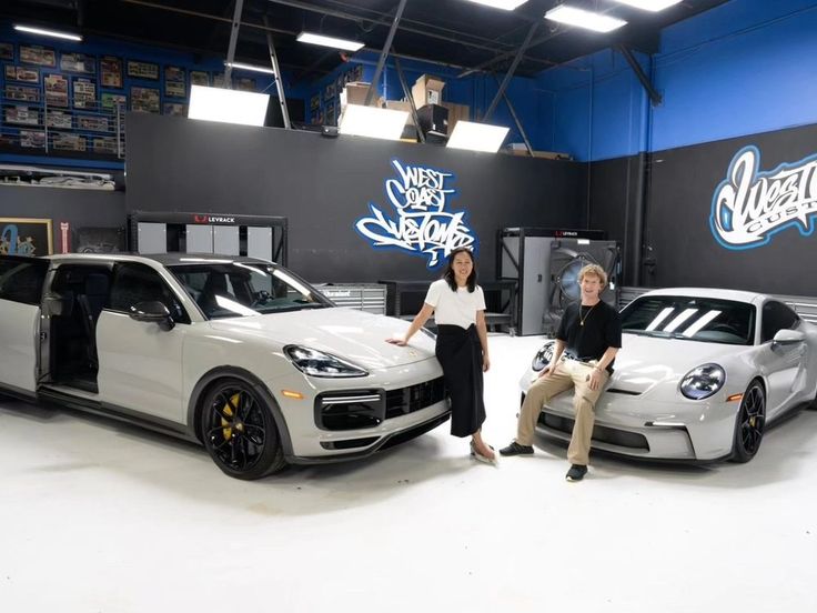 two women standing next to some cars in a garage