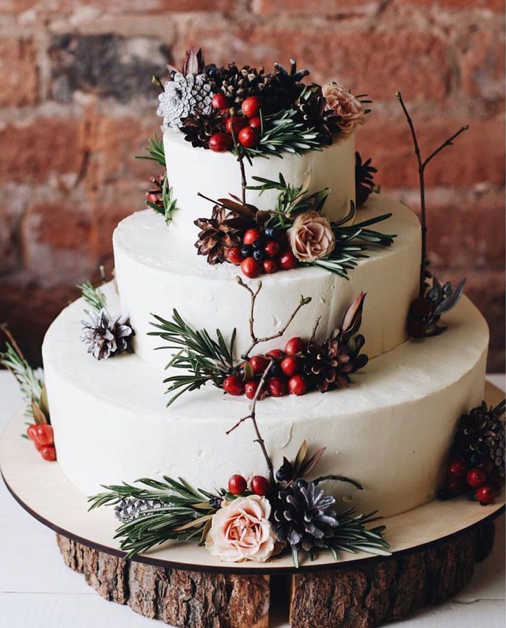 a three tiered cake with pine cones and berries