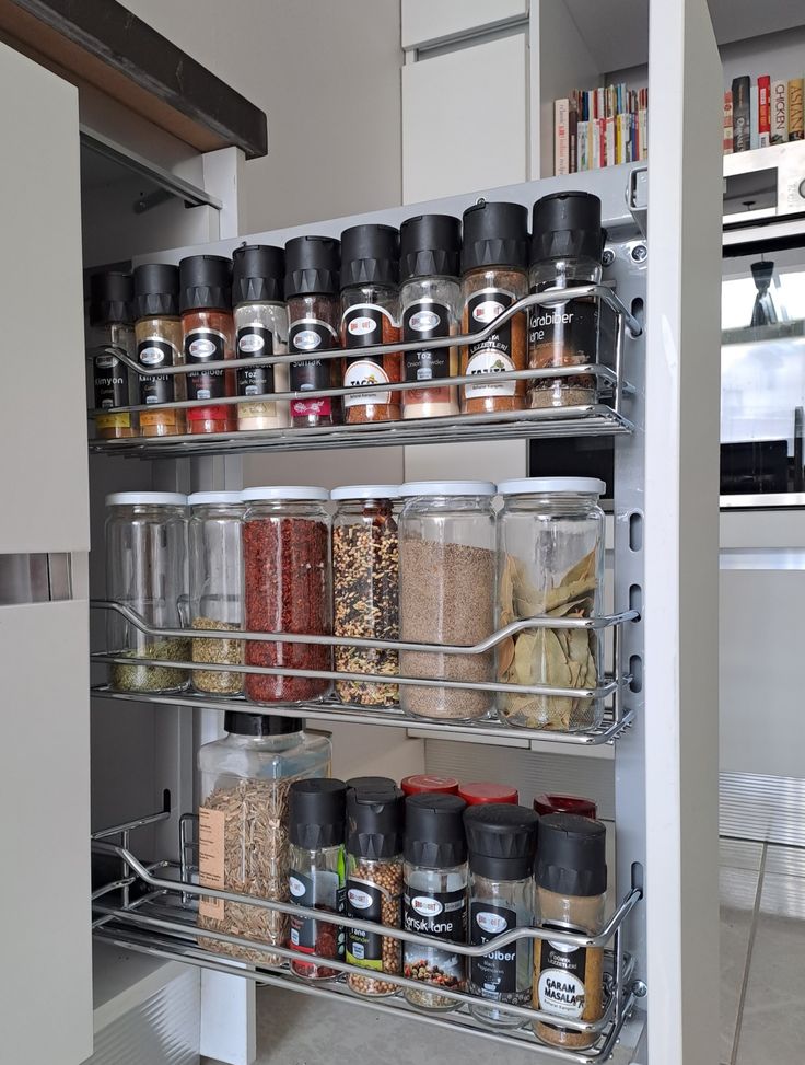 an organized spice rack in a kitchen with spices and seasonings on the bottom shelf