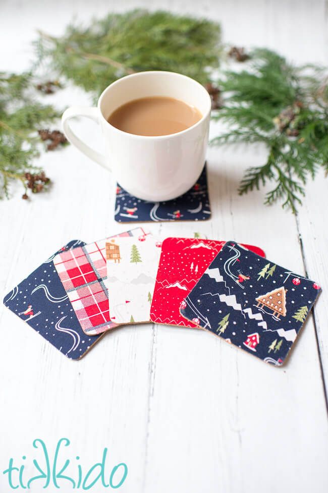 a cup of coffee sitting on top of a table next to coasters with christmas designs