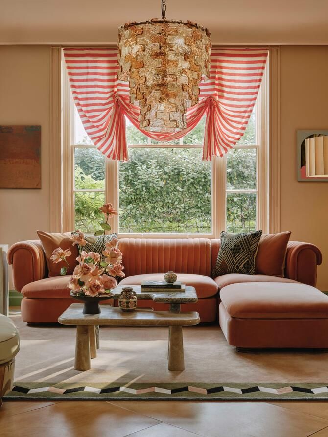 a living room filled with furniture and a chandelier hanging from the ceiling next to a window