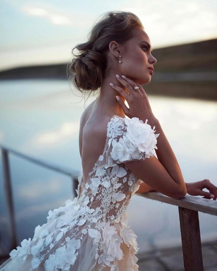 a woman in a white dress is standing on a railing with her hand on her shoulder