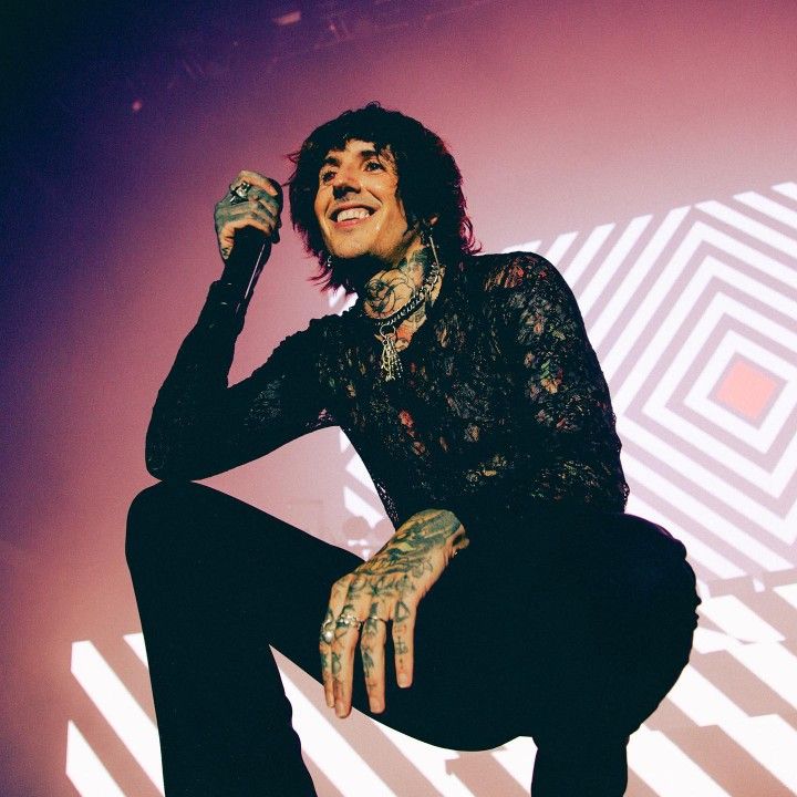 a man with tattoos and piercings sitting on a chair in front of a wall