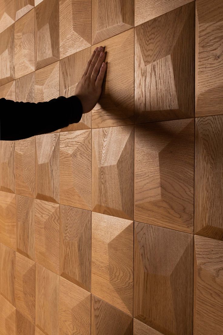 a person standing in front of a wall made out of wooden blocks with their hands on it