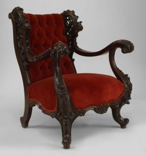 an ornately carved arm chair with red velvet upholstered seat