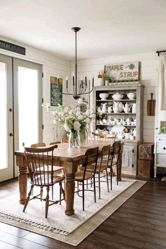 a dining room table with chairs and vases on it's centerpiece in front of an open door