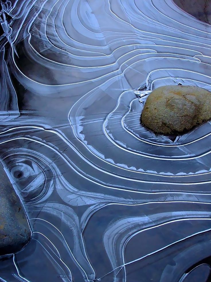 a rock sitting in the middle of a pool of water with ripples around it