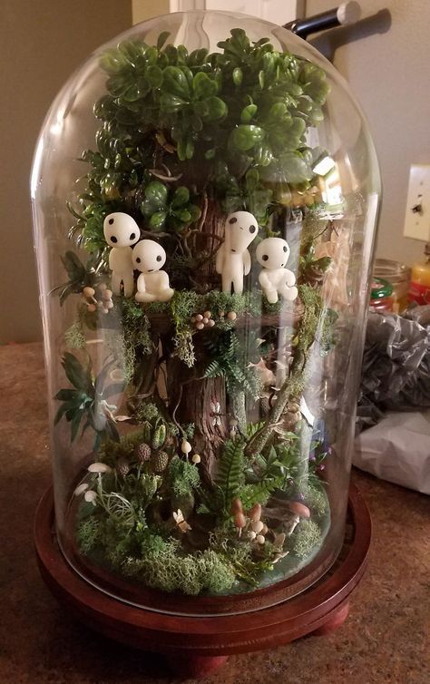 a glass dome filled with lots of plants and stuffed animals in the bottom part of it