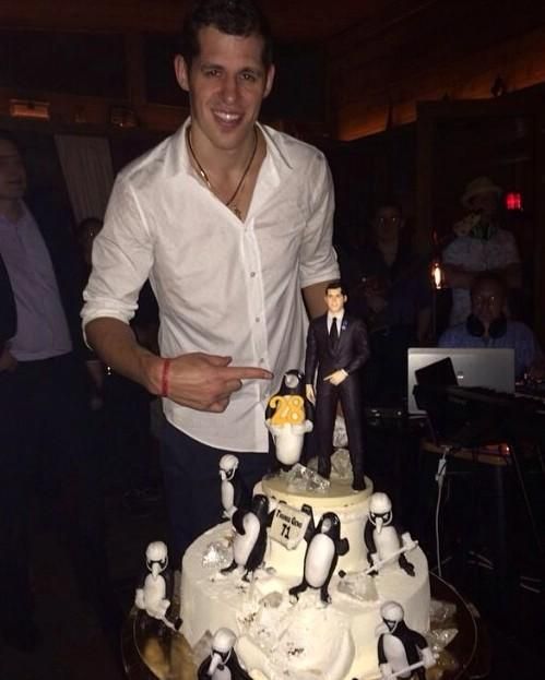 a man standing in front of a cake with penguins on it