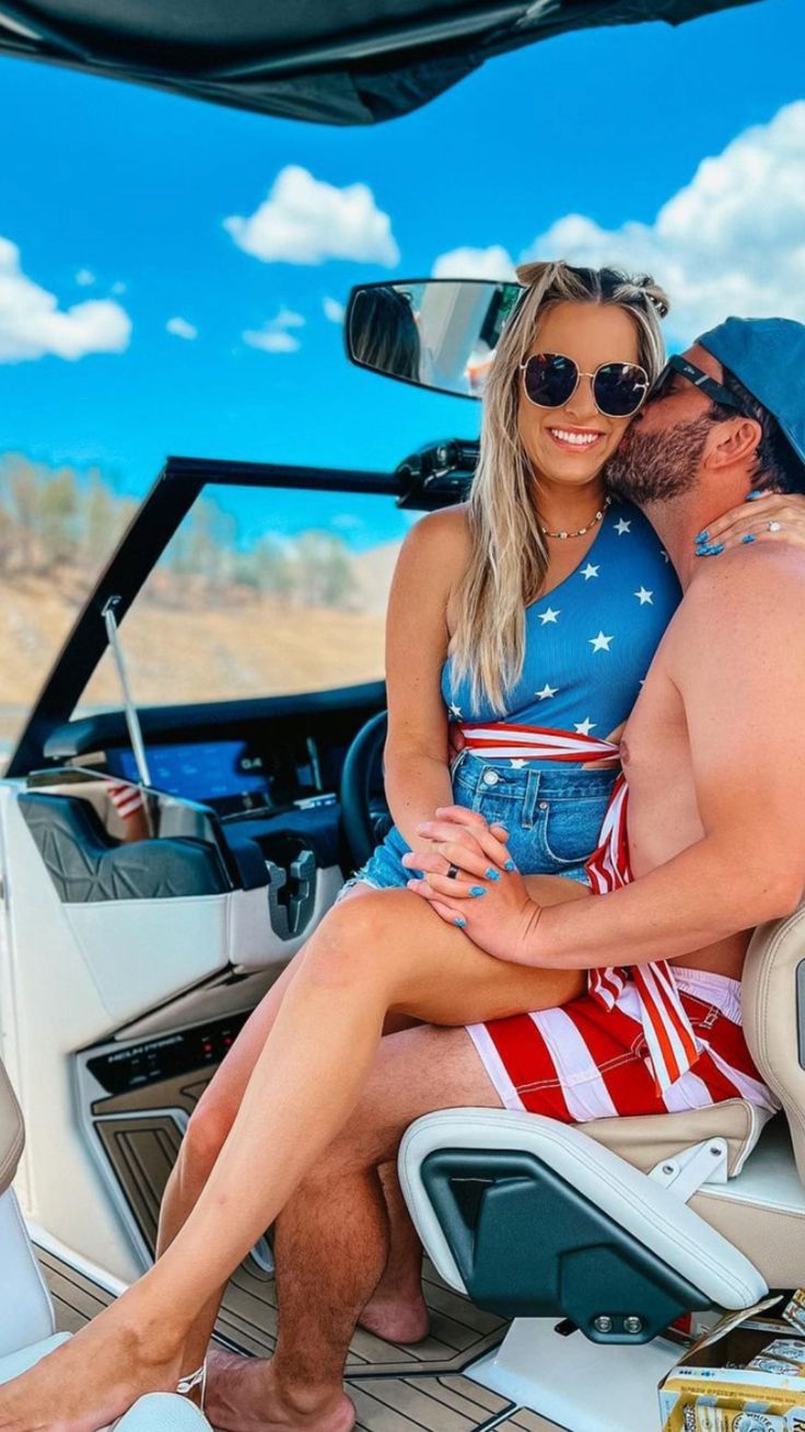 a man and woman are sitting on the back of a boat in the water with an american flag dress