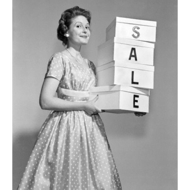 a woman holding stacks of boxes with the word sale spelled on them in front of her