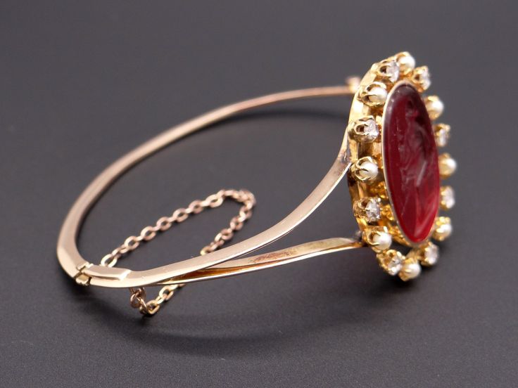 Jewelry Type: Bracelet Metal: 14k Yellow Gold Measurements: Length: 7 inch Top: 30mm x 25mm Markings: None ( scratch & acid tested) Weight: 17.2 grams Center: Oval Cut Venetian Glass w carved Intaglio Color: Red Measurements: 23mm x 18mm Accent Stones: 8 matching Rose Cut Diamonds Color: H Clarity: SI-1 Weight: 0.40cts total approx Accent Stones: 8 matching Round Pearls Color: White Measurements: 2.5mm #12219 Fine Jewelry Bracelet With Cabochon, Yellow Gold Cabochon Bracelets For Weddings, Luxury Intaglio Jewelry For Evening, Oval Cabochon Bracelet For Wedding, Oval Cabochon Wedding Bracelet, Luxury Cabochon Bangle Jewelry, Gold Intaglio Jewelry For Evening, Elegant Cabochon Bangle Jewelry, Luxury Cabochon Bracelets For Wedding