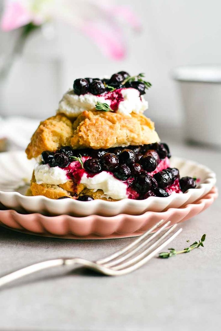 blueberry scones with whipped cream on a pink plate next to a silver fork