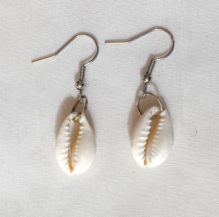 "These earrings are simple but beautiful, and perfect for any outfit and any occasion! They are made with a cowrie shell and a silver jump ring, earrings also come with rubber backings. Length: 1 3/4\" (from top of ear wire) Width: 1/2\" (shell) Due to it being handmade, earrings may differ slightly from pictures." Cheap Adjustable Shell Earrings, Nickel Free Adjustable Shell-shaped Earrings, Nickel-free Adjustable Shell-shaped Earrings, White Earrings With Ear Wire For Vacation, White Ear Wire Earrings For Vacation, Nickel Free White Jewelry For Vacation, Adjustable Silver Shell-shaped Earrings, White Teardrop Earrings For Beach, Nickel-free White Casual Jewelry