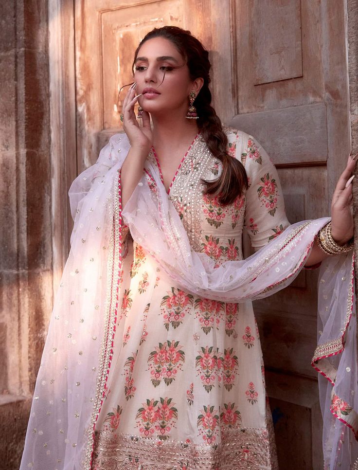 This pretty ensemble in floral jaal, combines gota and dori buttis with an intricate border embroidery. The short kurta with a dhoti embroidered in sequins and gold thread, adds a feminine grace. Off White Saree Set With Gota Work, Wedding Mulmul Palazzo Set With Dupatta, Wedding Palazzo Set With Dupatta In Mulmul, Off White Mulmul Bollywood Salwar Kameez, Festival Off White Mulmul Anarkali Set, Off White Bollywood Style Salwar Kameez In Mulmul, Festive Mulmul Sharara With Floral Embroidery, Off White Chanderi Palazzo Set With Gota Work, Wedding Sharara With Floral Embroidery In Mulmul