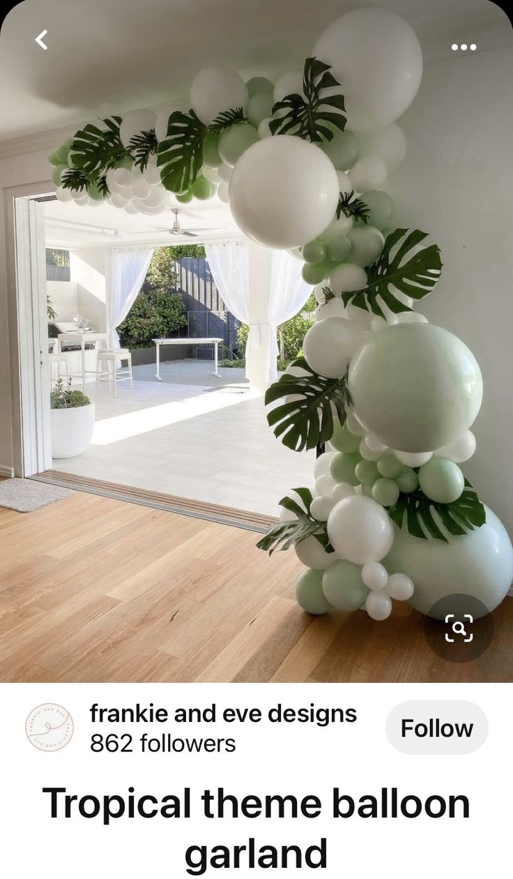 balloon arch with white and green balloons in front of an open door at the entrance to a house