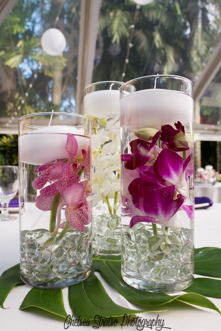 two vases filled with flowers and candles on top of a white tablecloth covered table