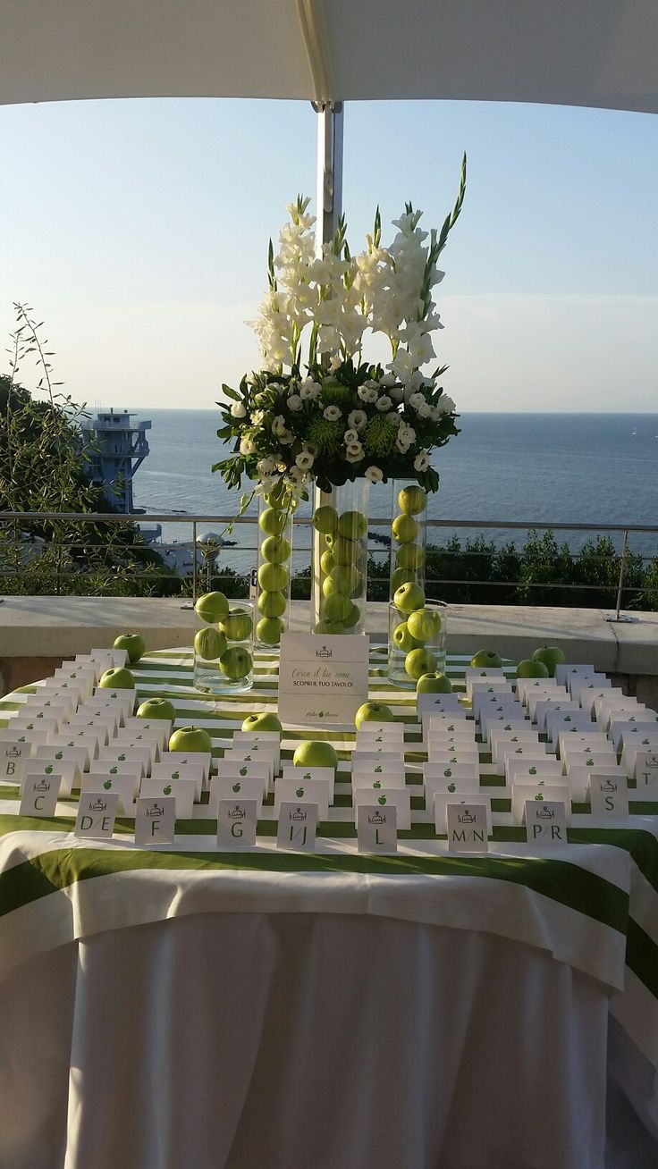 the table is set up for an event with flowers and place cards on it in front of the ocean