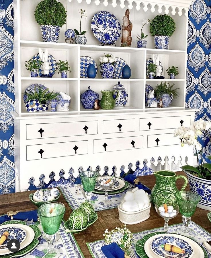 a dining room table with blue and white dishes on it, plates and vases