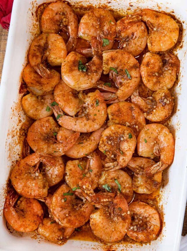 a white casserole dish filled with cooked shrimp