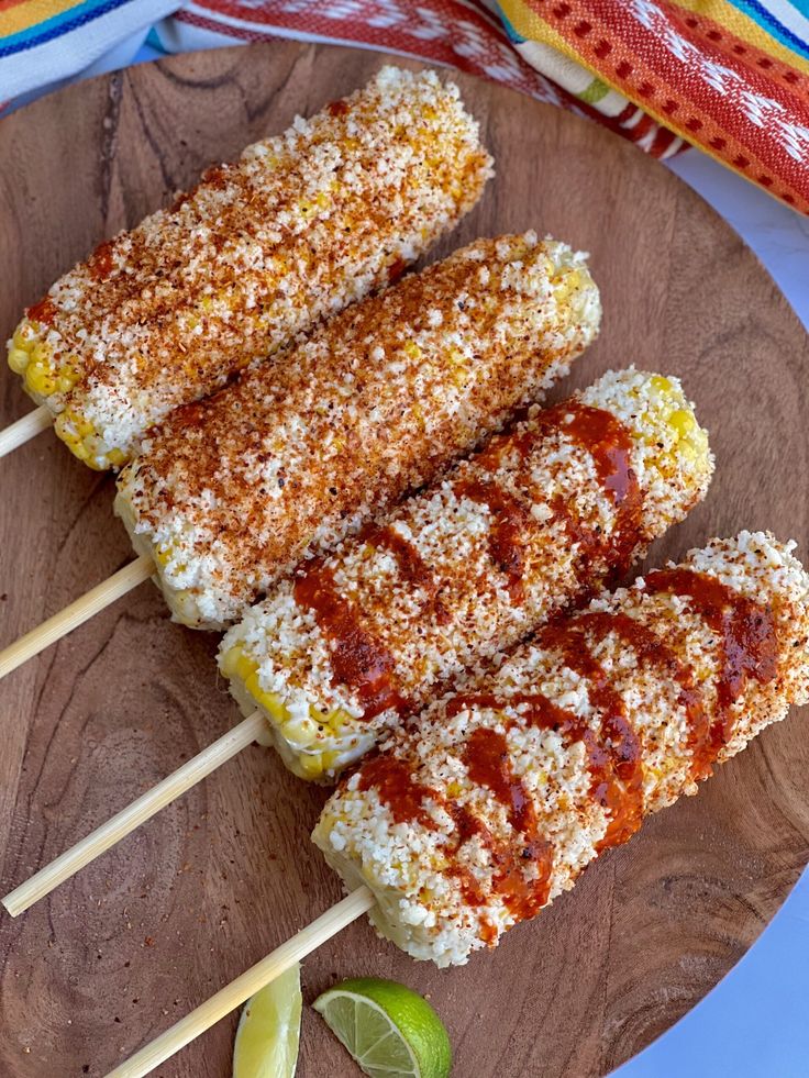 corn on the cob with ketchup and limes on a wooden plate