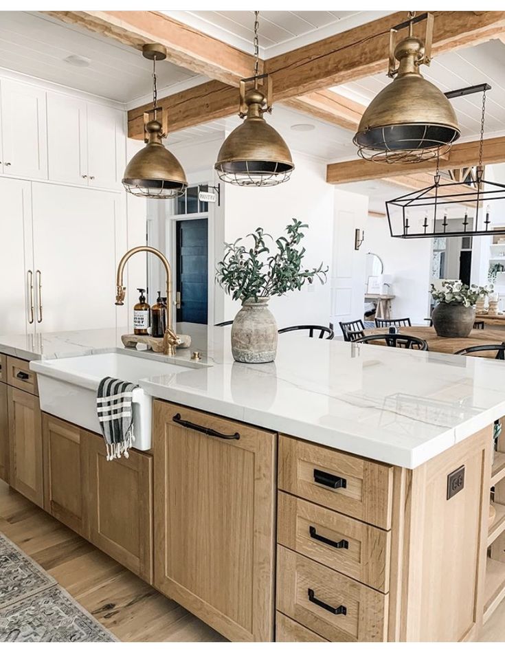 a large kitchen with an island in the middle and two pendant lights hanging from the ceiling