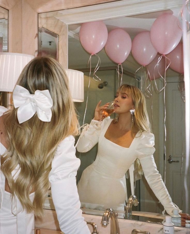 a woman in a white dress is brushing her teeth while looking at herself in the mirror