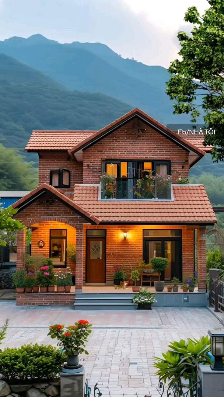 a large brick house sitting in the middle of a lush green field with mountains behind it