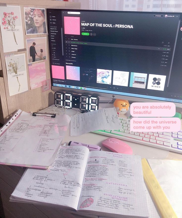 an open book sitting on top of a desk next to a computer monitor and clock